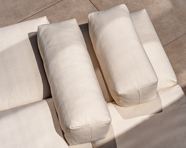 Coussins Vetsak en tissu outdoor, de couleur écrue, captés en plein soleil sur une terrasse en pierre. Coussins Vetsak en tissu outdoor, de couleur écrue, captés en plein soleil sur une terrasse en pierre.